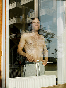 光着胸膛站在窗前的男人图片