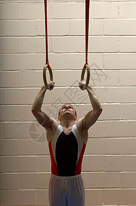体操项目吊环从吊环上垂下的男子体操运动员背景