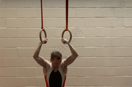 吊环运动运从吊环上垂下的男子体操运动员背景