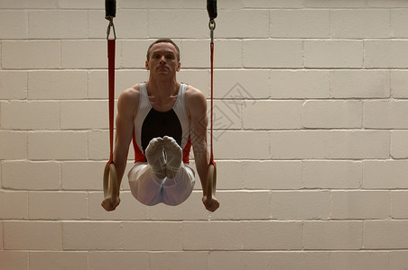 男子体操运动员在吊环上保持平衡图片