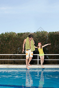 父亲和女孩在游泳池里蘸脚趾图片