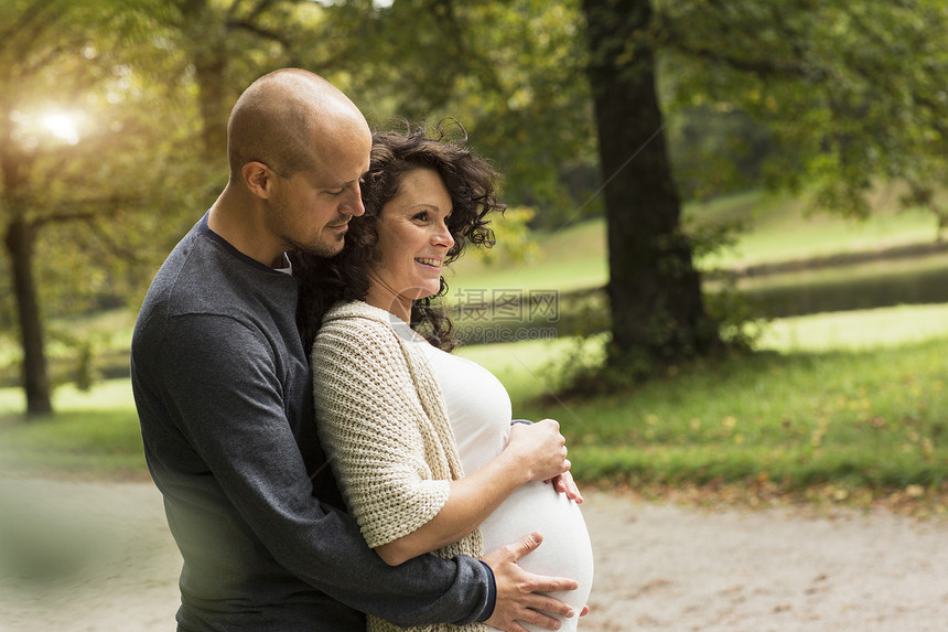 在公园里爱抚肚子的怀孕夫妇图片