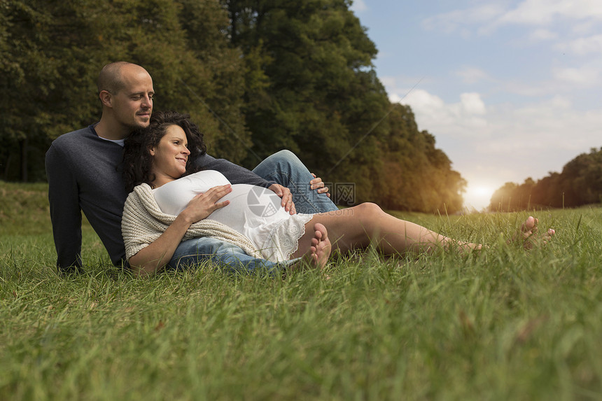 坐在公园草地上的怀孕夫妇图片