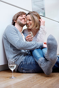 夫妇俩坐在厨房地板上喝酒高清图片