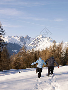 一对在雪中跑向山的夫妇高清图片