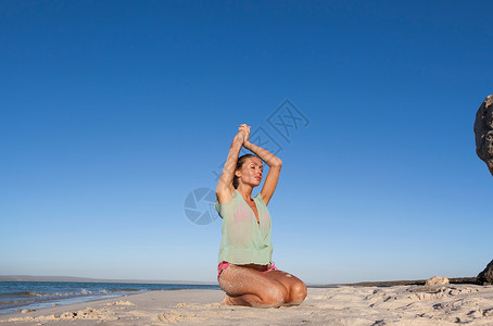 穿着比基尼的女人跪在海滩上图片