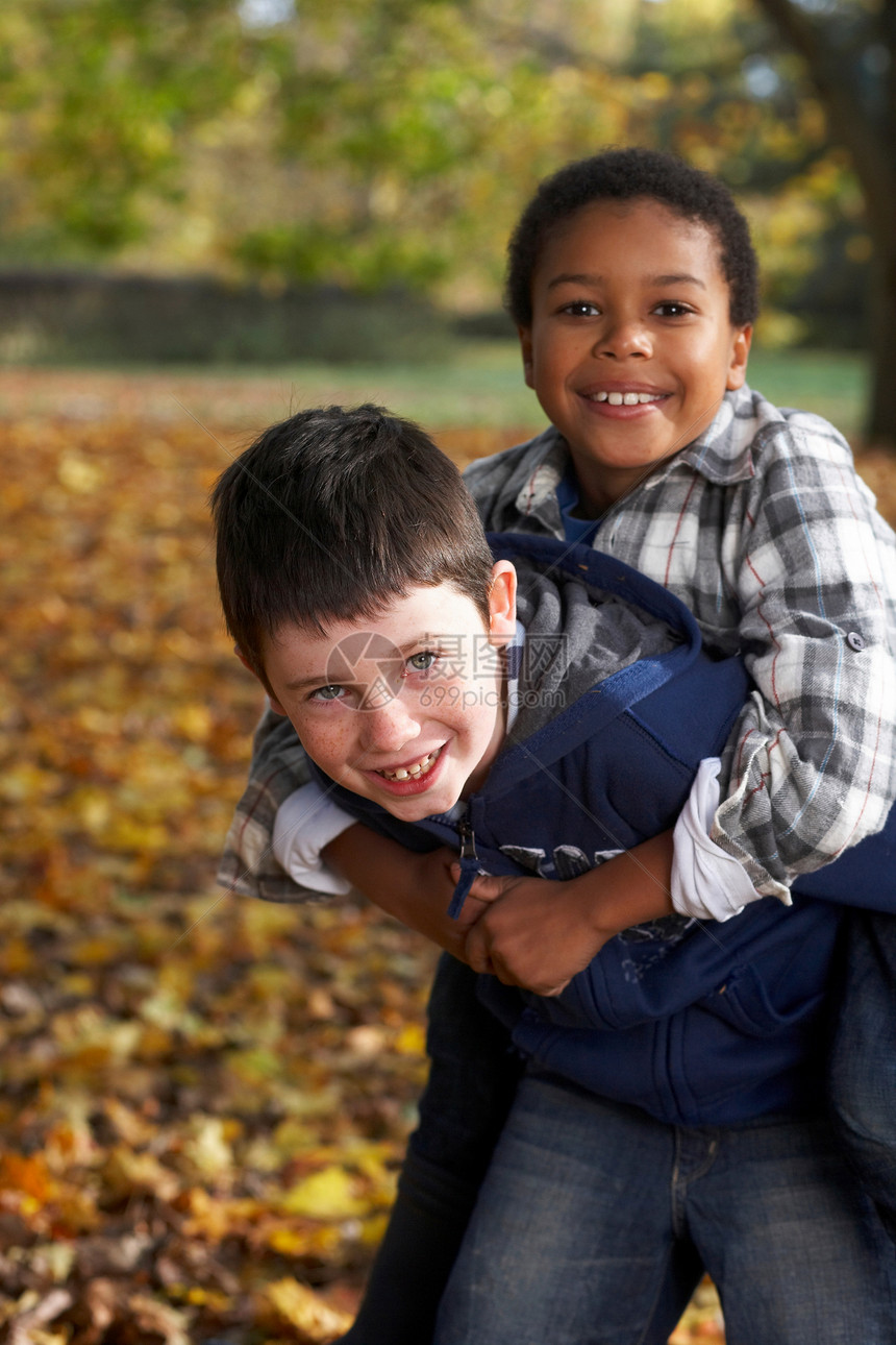 两个男孩在秋叶里玩耍图片