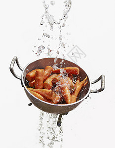 水和新鲜胡萝卜一起从漏勺里掉出来背景图片