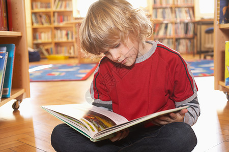 坐图书馆男孩在地板上看书背景