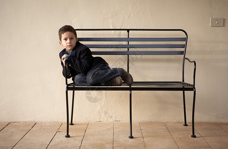男孩坐在户外的长椅上图片
