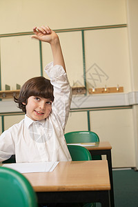 男孩在教室里举起手来书桌高清图片素材