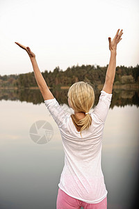 年轻女子在湖边跳舞，伸展身体图片