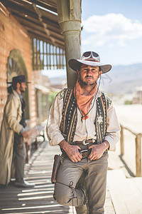 西班牙阿尔梅里亚塔伯纳斯布拉沃堡野生西部电影集上靠在柱子上的牛仔肖像图片