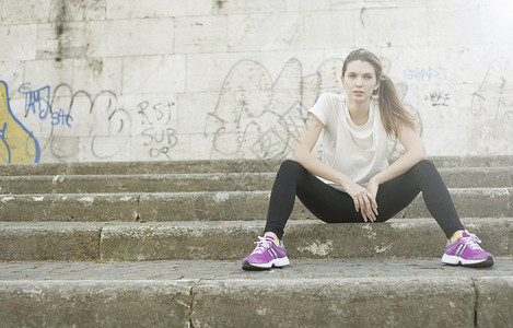 白鞋涂鸦素材坐在台阶上的运动型年轻女子背景
