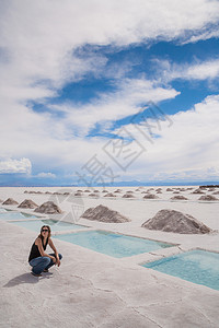 阿根廷科尔多瓦省萨利纳斯格兰德斯盐场的一位妇女坐在水池旁图片