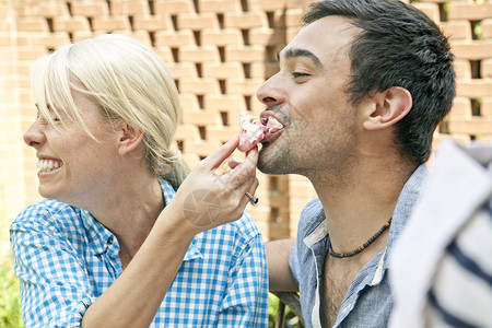 在花园聚会上吃蛋白酥饼的年轻夫妇图片