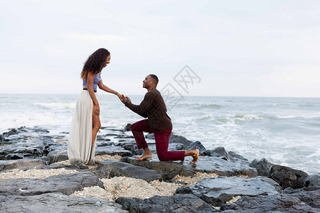 男子跪在海边的岩石上求婚图片