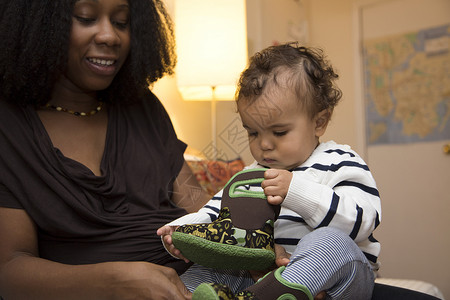 婴儿战利品中年妇女和好奇的带婴儿靴的幼童女儿背景