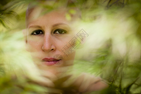 树叶中患癌症的年轻女子的特写肖像图片