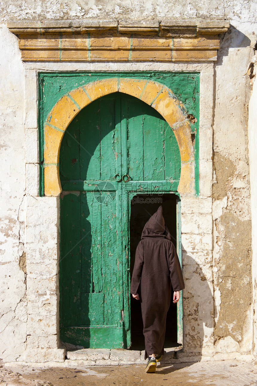 穿着传统服装的男人走进门的后视图，摩洛哥，伊萨乌伊拉图片