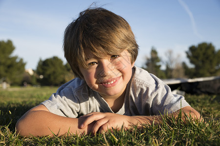 躺在公园草地上的微笑男孩的肖像图片