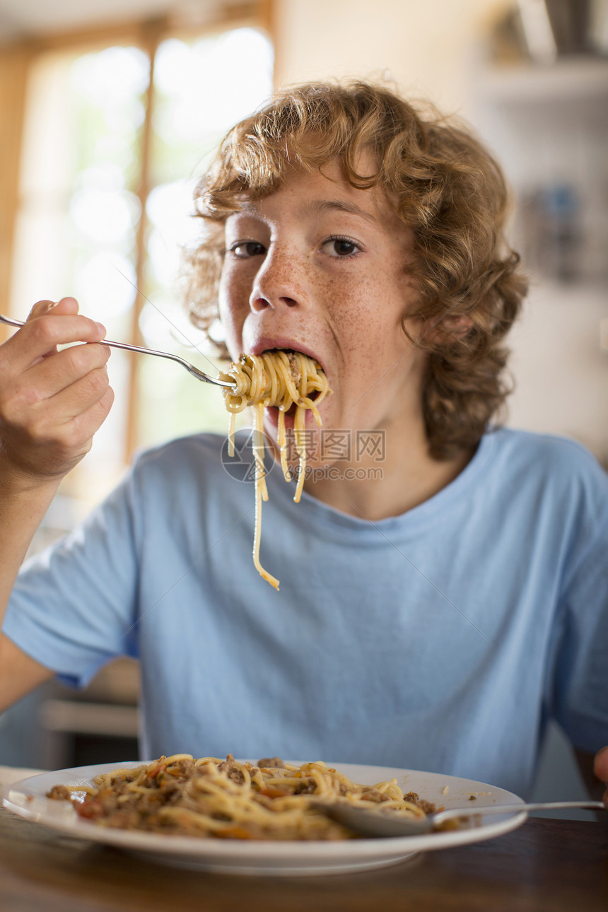十几岁的男孩在餐桌上吃意大利面图片