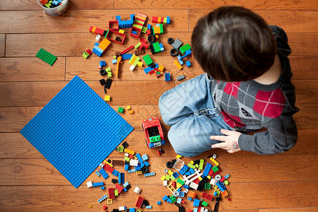 8岁孩子男孩在地板上玩玩具块背景