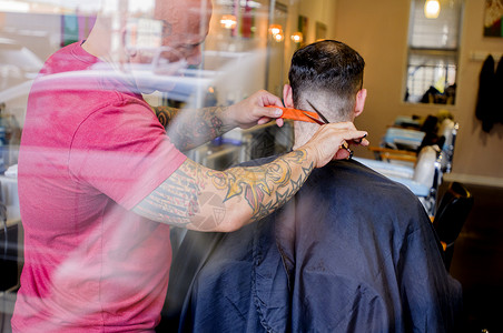 带纹身的理发师剪发的年轻人背景