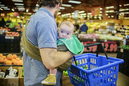 爸爸抱着儿子和购物篮在超市里高清图片