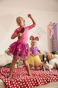 女孩和妹妹在床上用麦克风跳舞唱歌图片