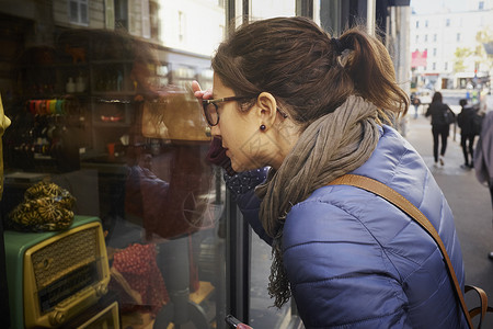 中年妇女透过古董店橱窗窥视背景图片