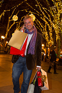 在西班牙马略卡绿树成荫的大街上圣诞购物男性打电话图片