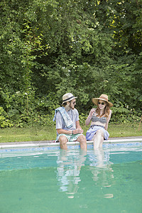 一对夫妇把腿伸进游泳池图片