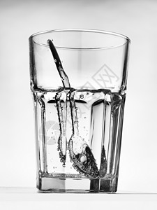水玻璃中的银茶匙的静物背景图片