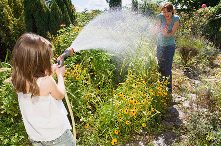 花园软管女孩向母亲喷水背景
