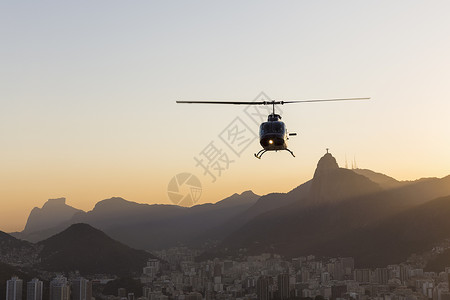 巴西里约热内卢黎明时分的直升机和救世主基督的剪影图背景图片