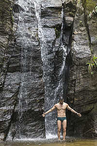 巴西里约热内卢蒂华卡森林瀑布前张开双臂站着的成熟男人图片