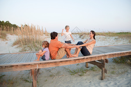 家人一起坐在沙滩走道上背景图片