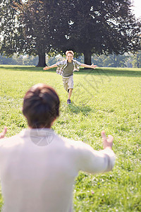在公园里跑向他父亲的男孩图片