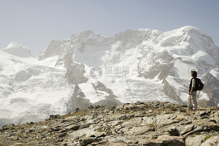 在冰雪覆盖的山附近徒步旅行的人图片