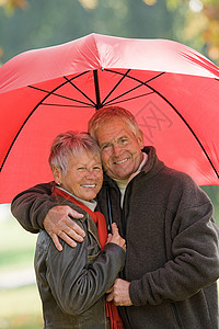打红色雨伞的老年夫妇背景图片