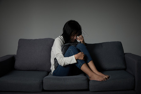 委屈巴巴年轻女性坐在沙发上哭泣背景