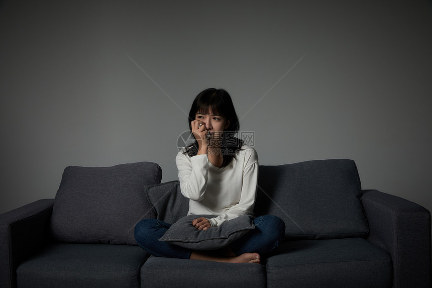 年轻女性坐在沙发上哭泣图片