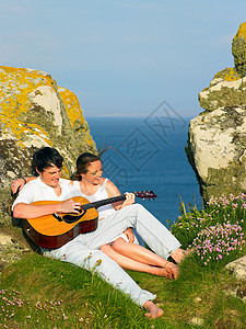 在悬崖上弹吉他的情侣图片