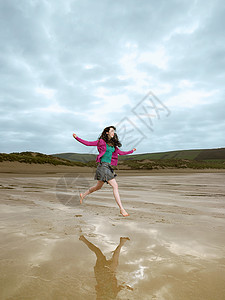 年轻女子在沙滩上跳跃图片