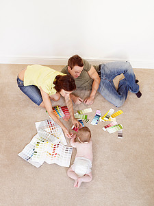 地板上有彩色样品的年轻家庭图片