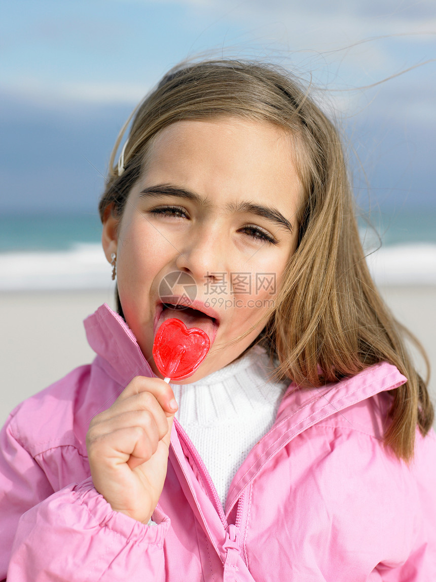 海边抱棒棒糖的小女孩图片