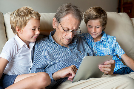 家庭wifi在看数字平板电脑的祖父和孙子背景