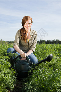 用水罐浇灌田里的庄稼的女人图片