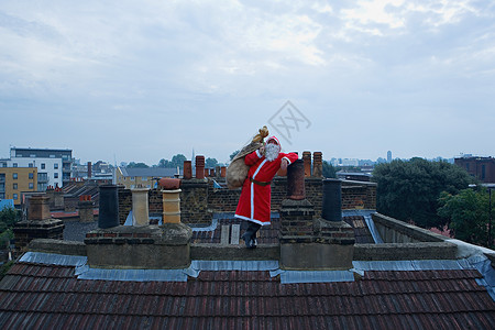 圣诞老人爬烟囱站在屋顶上的圣诞老人背景